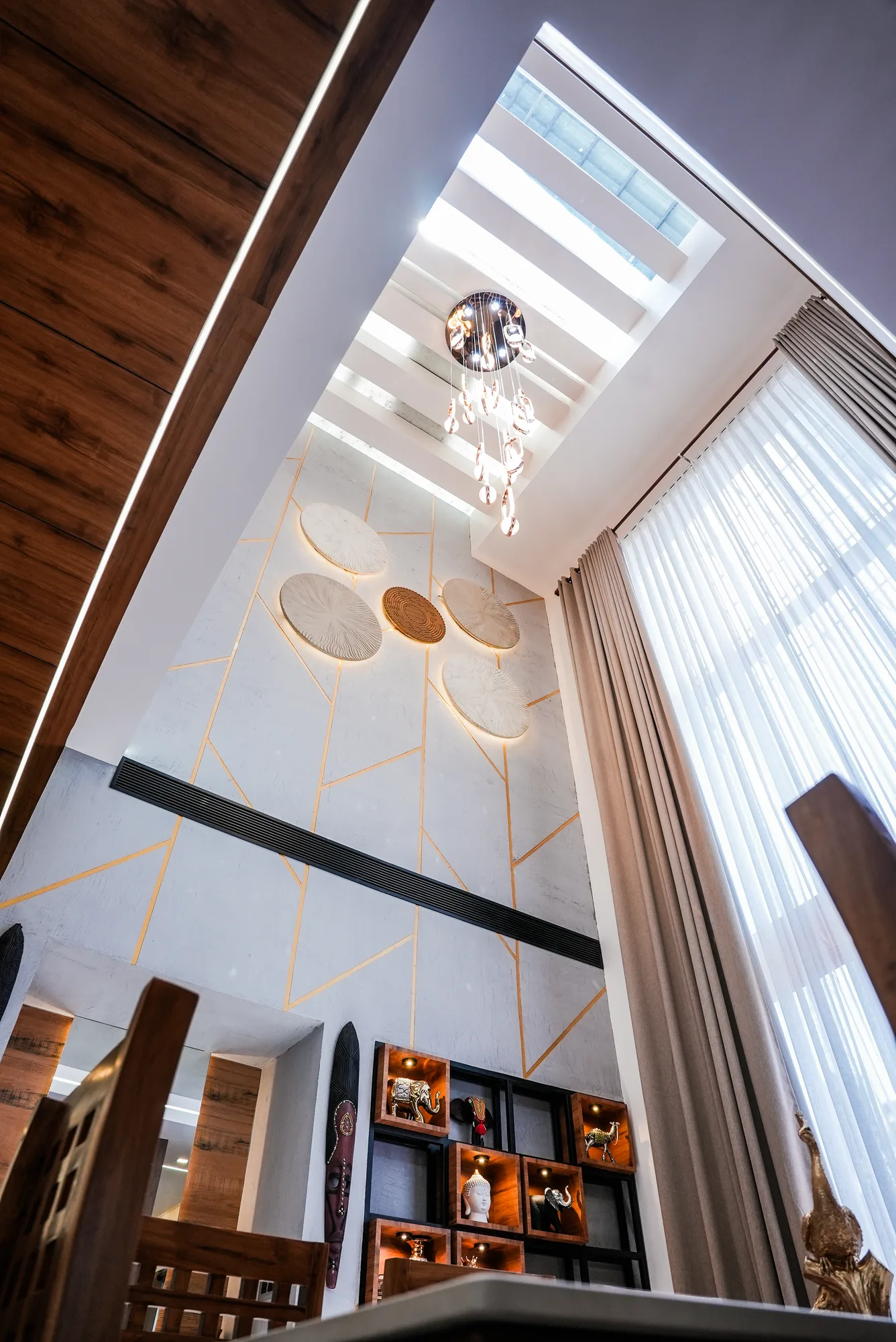 Double-height dining space with chandelier at Sanpra Pranavam